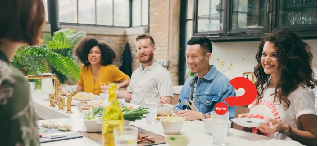 Friends sharing dinner and conversation around an Alpha table
